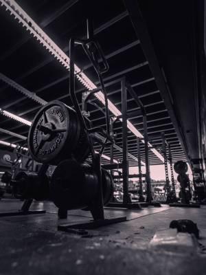 A low-angle grayscale gym inside view with a barbell and other pieces of equipment around